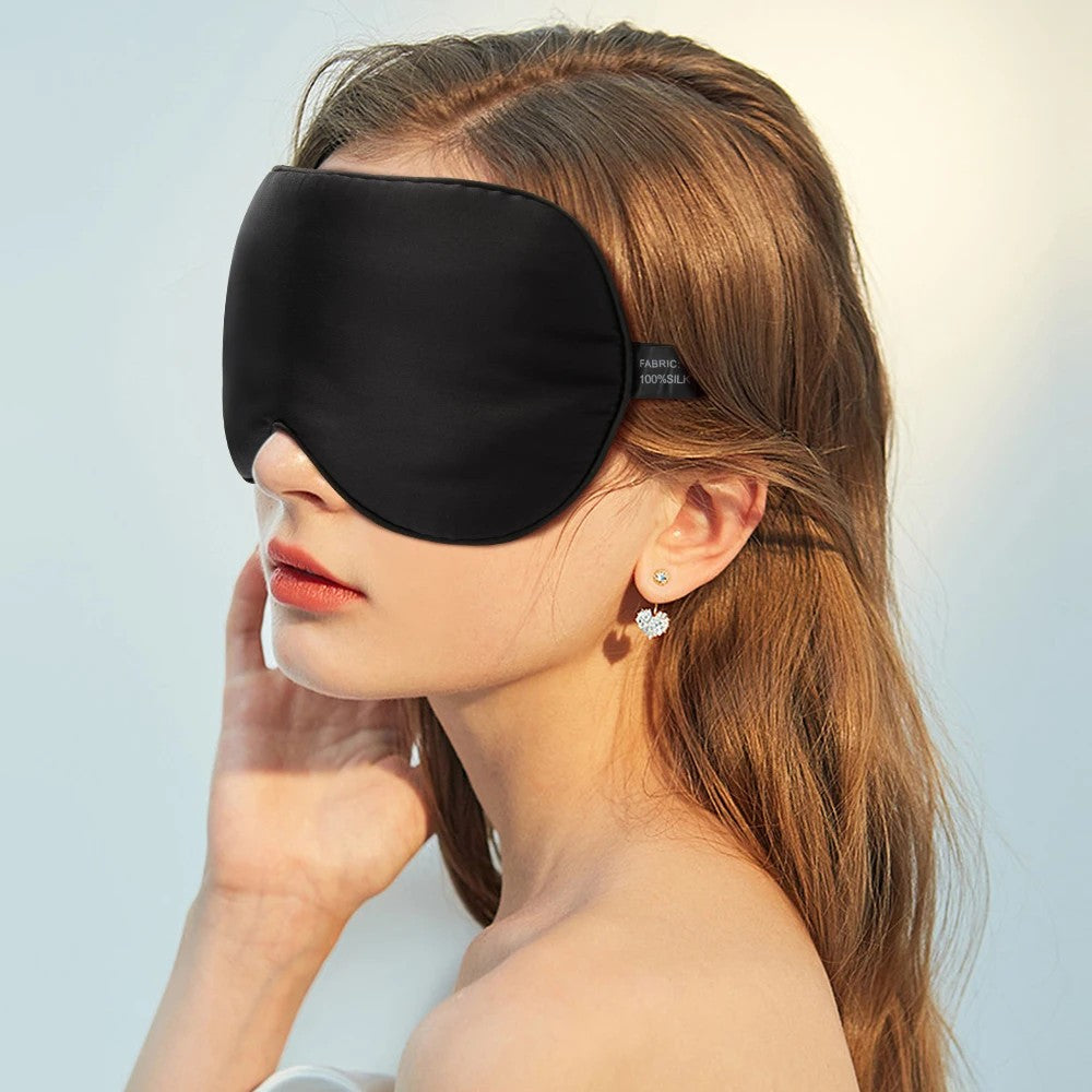 Femme portant un masque de nuit en soie noire, fond clair